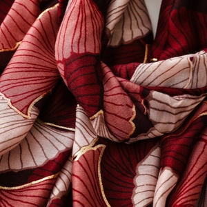 Close-up of soft cotton-linen scarf featuring golden ginkgo leaf print and fine texture