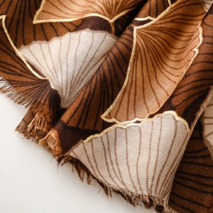 Detail of soft cotton-linen shawl with golden ginkgo leaf prints and fringe edge