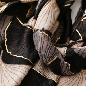 Macro detail of golden ginkgo leaf patterns with metallic outlines on black cotton scarf