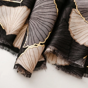 Detail of soft ginkgo leaf printed scarf with golden foil edges and frayed fringe
