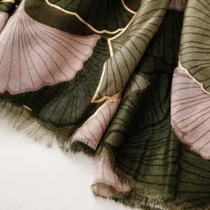 Close-up of ginkgo leaf print scarf with gold foil details and fine fringe tassels