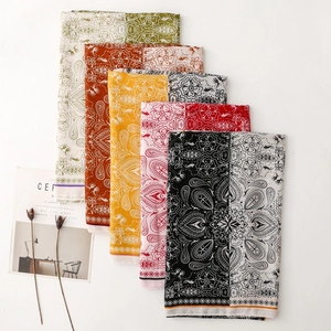 Flat lay of multiple paisley print scarves in various colors with artistic magazine props