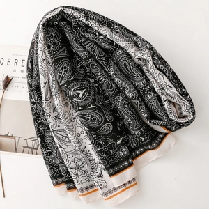 Close-up of black and white paisley scarf with floral patterns and orange striped edges
