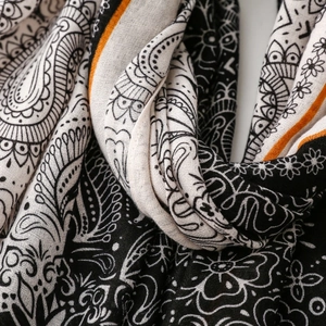 Close-up of paisley print shawl with soft texture and vibrant orange border detail