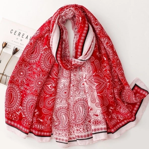 Macro detail of red and pink paisley pattern scarf with elegant floral edge details