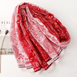 Detailed view of red and white paisley print scarf with fringe edges and cereal magazine