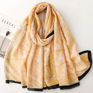 Detail of a chic ginger yellow hand-painted print scarf with stylish black borders
