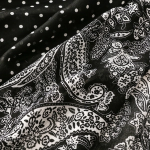 Macro detail of black and white scarf showing contrast paisley and polka dot textures