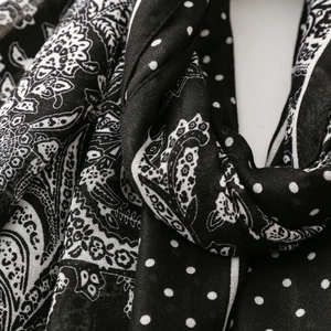 Macro shot of black and white paisley and polka dot printed scarf in soft silk fabric