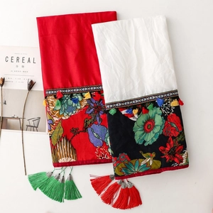 Detail of red and white ethnic shawls featuring floral embroidery and tassels