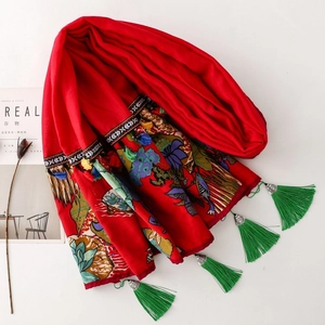 Detail of red ethnic shawl with floral embroidery and vibrant green tassel accents