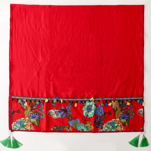 Detail of red floral embroidery on scarf with colorful fringe and green tassels