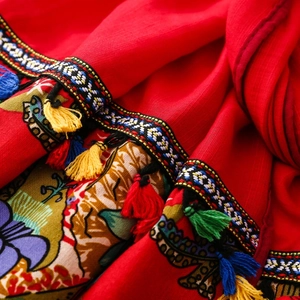Close-up of red shawl with ethnic embroidery and colorful handmade tassels and fringe