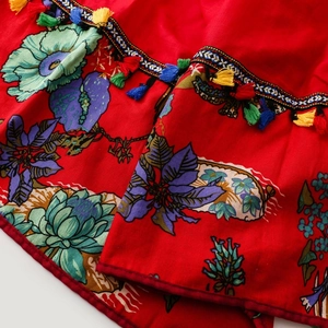 Detailed close-up of ethnic red cotton shawl with floral print and colorful tassels