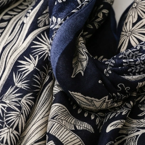 Detailed view of dark blue scarf featuring white palm leaf and sunflower floral patterns