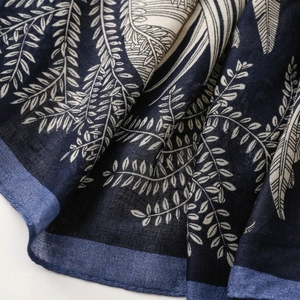 Close-up of deep blue cotton scarf featuring detailed white leaf pattern texture