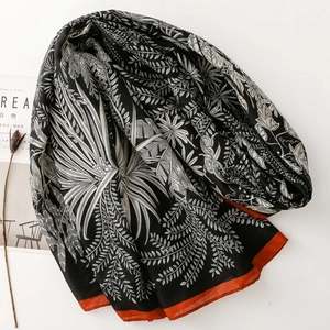 Elegant black and white tropical leaf pattern scarf with vibrant orange border accents