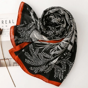 Close-up of black and white scarf featuring wheat leaf patterns and orange borders