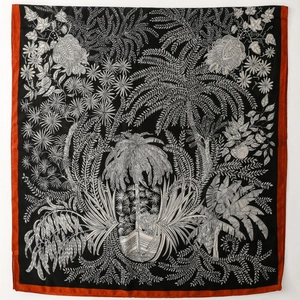 Detail of tropical plant motifs and floral patterns on black silk scarf with orange border
