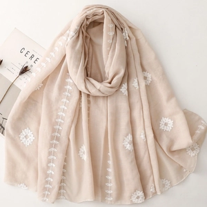 Elegant beige embroidered scarf with white floral patterns and tassel details