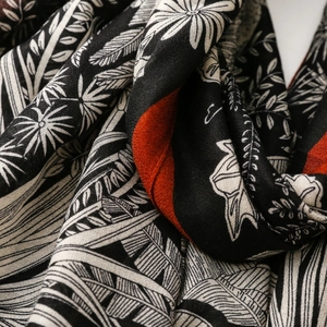 Detailed close-up of wheat and floral patterns on soft black and orange cotton scarf