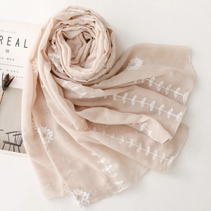 Detail of apricot embroidered scarf with floral patterns on lightweight linen fabric