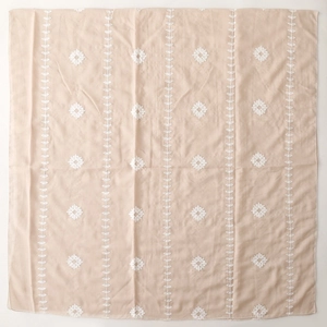 Close-up of beige ethnic scarf with white embroidery and intricate geometric leaf patterns