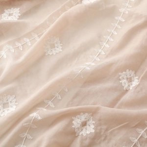 Close-up of elegant floral embroidery on beige lightweight fabric scarf shawl