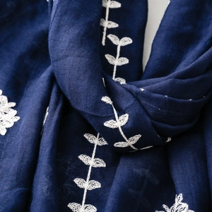 Close-up of white leaf embroidery on navy blue ethnic style scarf fabric