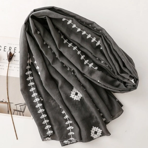Detailed embroidery on a dark grey ethnic scarf with delicate white floral patterns