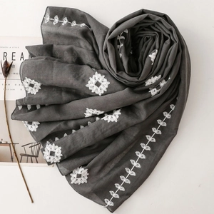 Detailed close-up of dark grey scarf with delicate white floral embroidery and soft texture