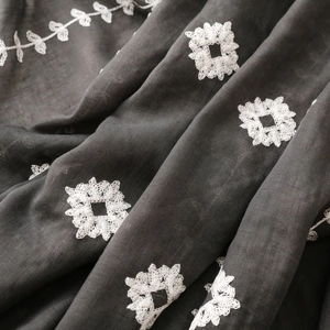 Detailed close-up of dark grey cotton linen scarf with elegant white floral embroidery
