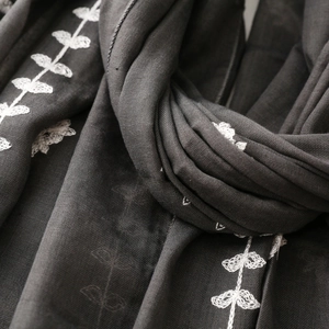 Macro shot of dark grey ethnic scarf featuring white leaf embroidery and textured fabric