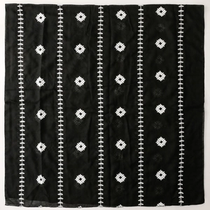 Macro view of white leaf embroidery details on a black ethnic style scarf fabric