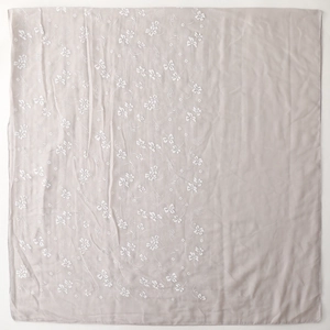 Detailed macro view of embroidered white floral patterns on a light purple linen scarf