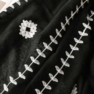 Detailed close-up of white floral embroidery on a black ethnic style cotton linen scarf