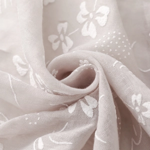Detail of light pink floral embroidery and delicate polka dots on soft sheer fabric