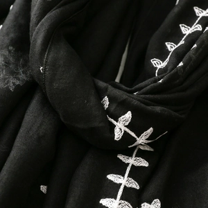 Macro view of white embroidery on black scarf fabric showing texture and stitches