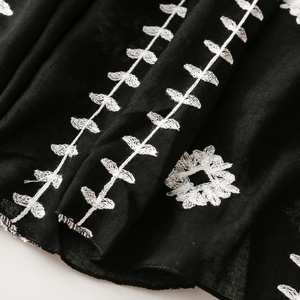 Macro shot of white floral embroidery detail on lightweight black cotton linen scarf