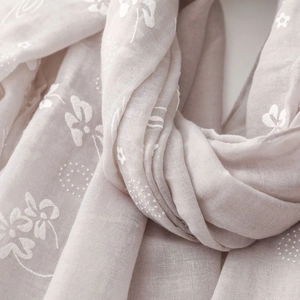 Macro detail of breathable cotton linen scarf with elegant white floral embroidery