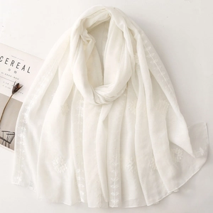 Detailed view of delicate white floral embroidery on translucent lightweight scarf