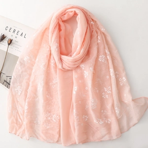 Flat lay of pink cotton linen scarf with white floral print and lifestyle magazine props
