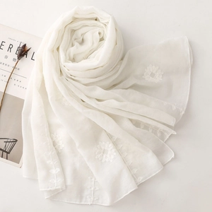 Detailed view of elegant white floral embroidery on a lightweight cotton linen shawl