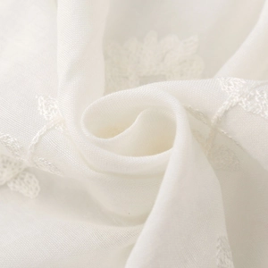 Macro shot of ivory white scarf fabric with delicate ethnic floral embroidery details