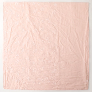 Detail of light pink linen scarf featuring delicate white floral patterns and soft texture