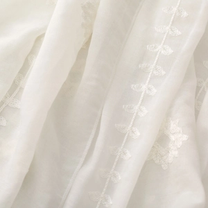 Close-up of white ethnic embroidery on a lightweight and breathable sheer scarf