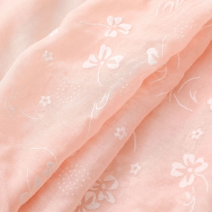 Detail of pink cotton linen scarf featuring delicate white floral embroidery and soft texture
