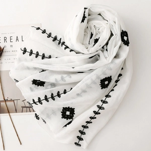 Detail of white embroidery scarf with black floral patterns and leaf stitching