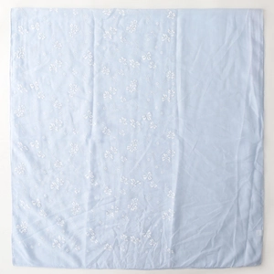 Detail of light blue linen scarf featuring delicate white floral embroidery and fine hem stitching