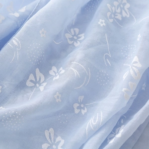 Close-up of light blue cotton linen scarf with delicate white floral embroidery patterns